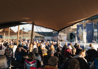 Audience under a stretch tent watching Julius Caesar