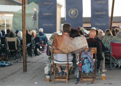 A couple in the audience hugging with a blanket wrapped around them as they watch the performance